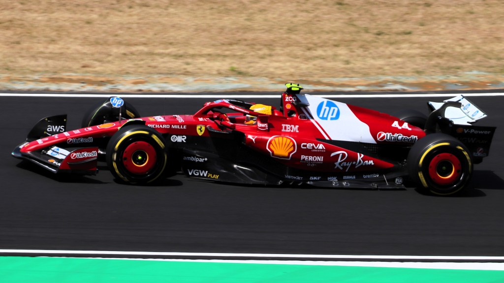 A Ferrari Formula 1 car in Rosso Corsa red racing on a track, showcasing its sleek design and sponsor logos.
