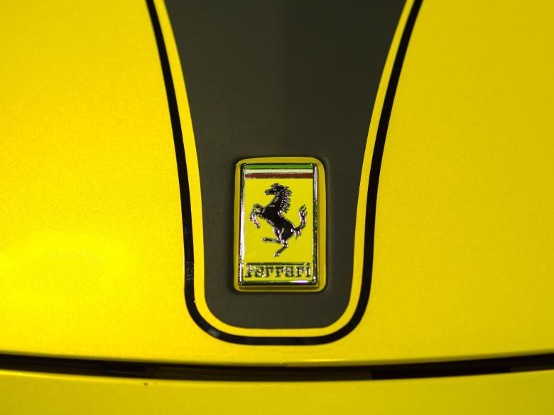 Close-up of the Ferrari emblem featuring a black prancing horse on a yellow background, highlighted by a sleek design.