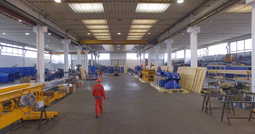 Interior view of OM Siderurgica's manufacturing facility featuring equipment and materials for complex material handling systems.