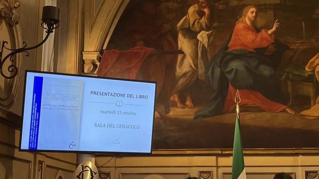 A presentation screen displaying information about the book 'Artificial Intelligence in Public Administration' in a historical setting with a mural in the background.